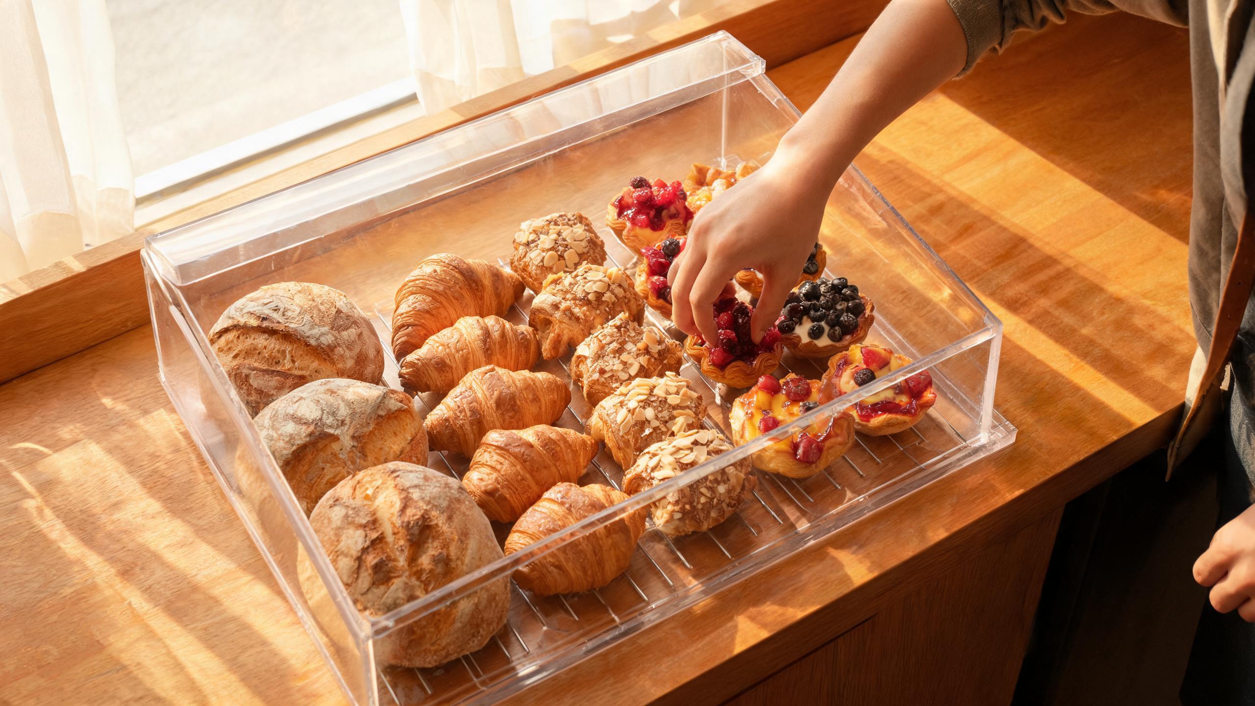 Customer selecting pastry from acrylic bakery display case